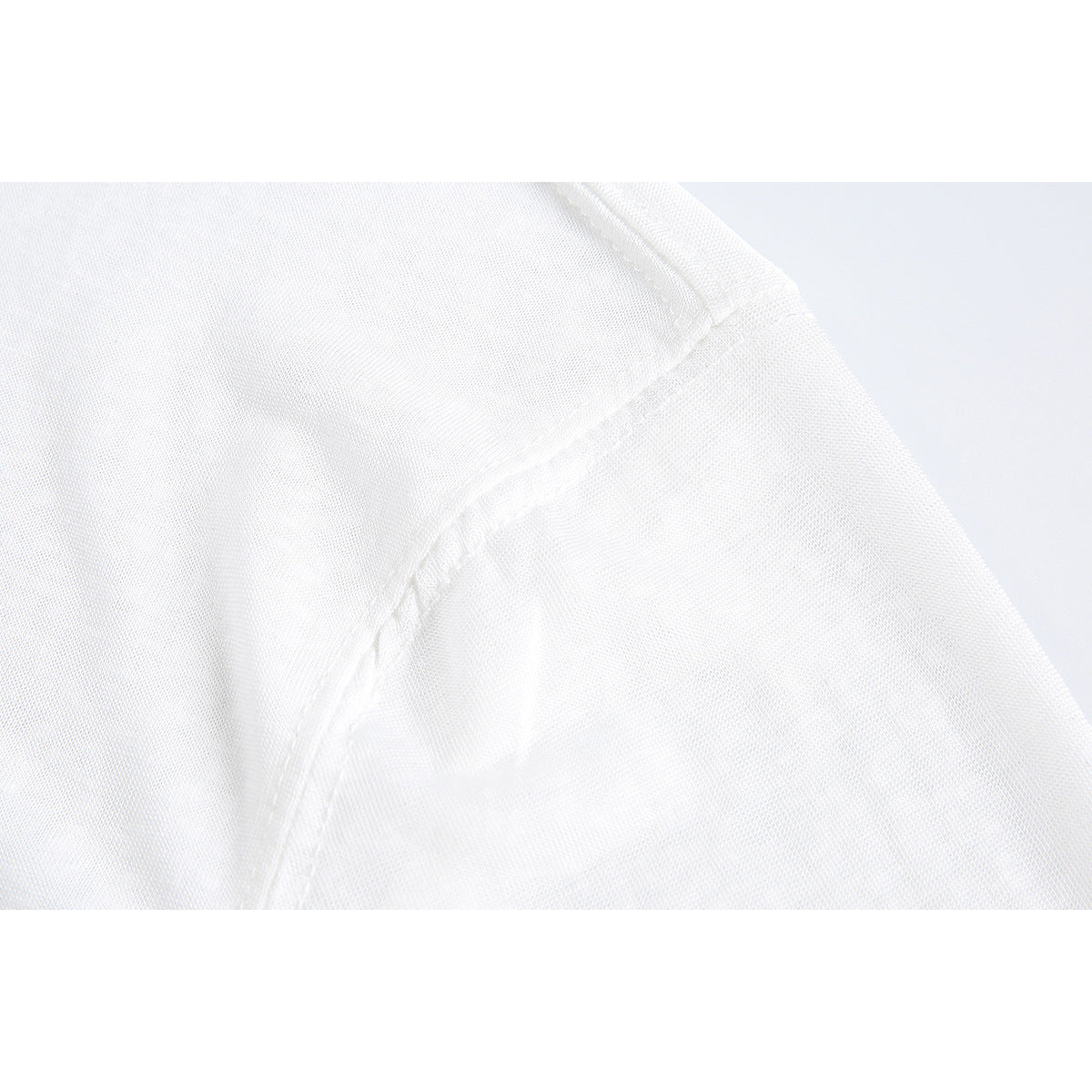 Close-up of a white shirt's shoulder seam and sleeve construction.