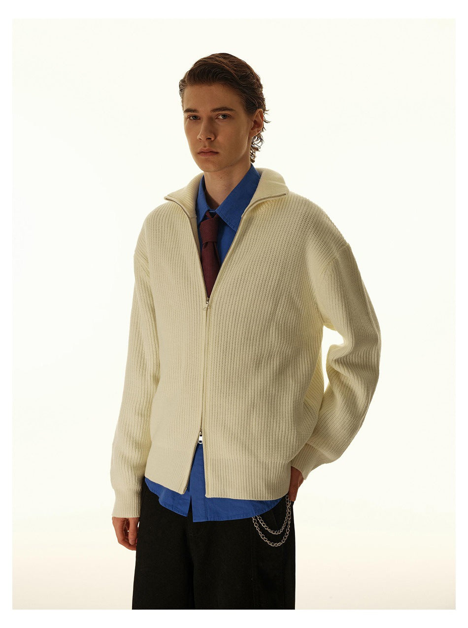Model wearing a cream ribbed zip-up cardigan over a blue shirt and burgundy tie, shown from the front.