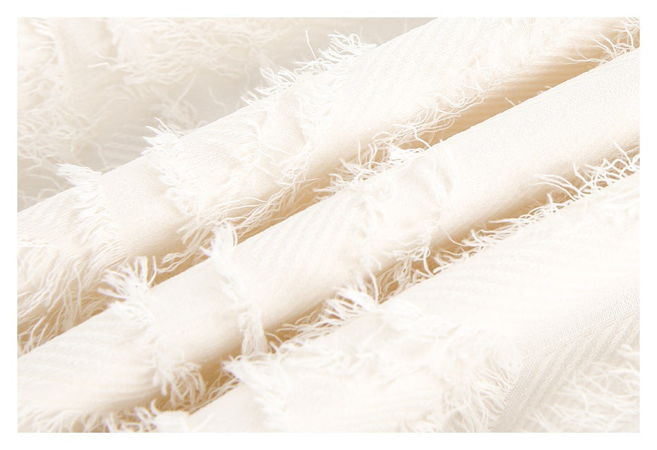 Close-up of ivory fabric strips with loose fringe and a visible woven texture.