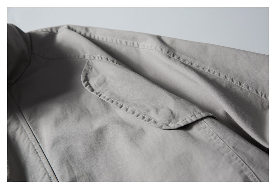 Close-up of a gray jacket’s curved flap pocket and shoulder seam.