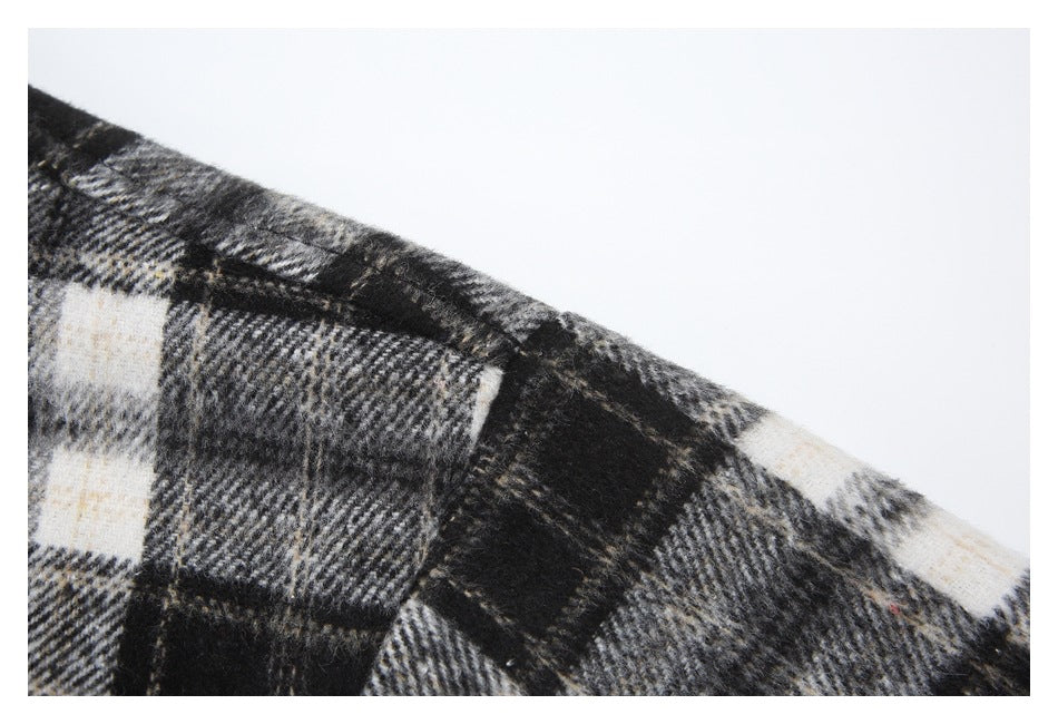 Close-up of the garment's black, gray, and cream plaid fabric and shoulder seam.