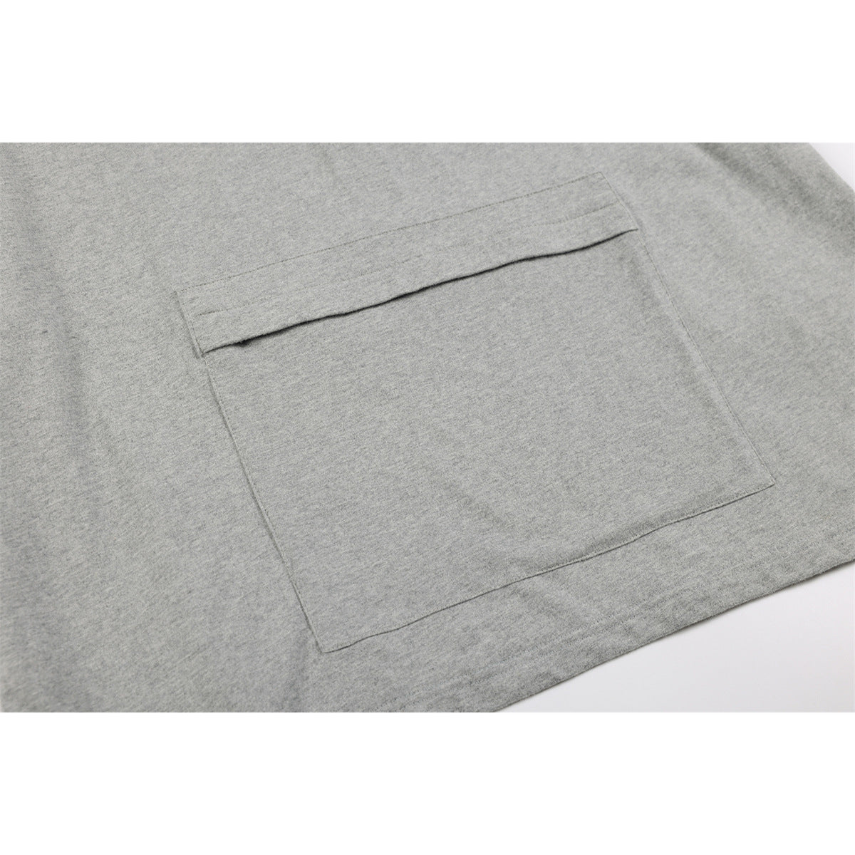 Close-up of a large patch pocket with a folded top edge on a heather gray shirt.