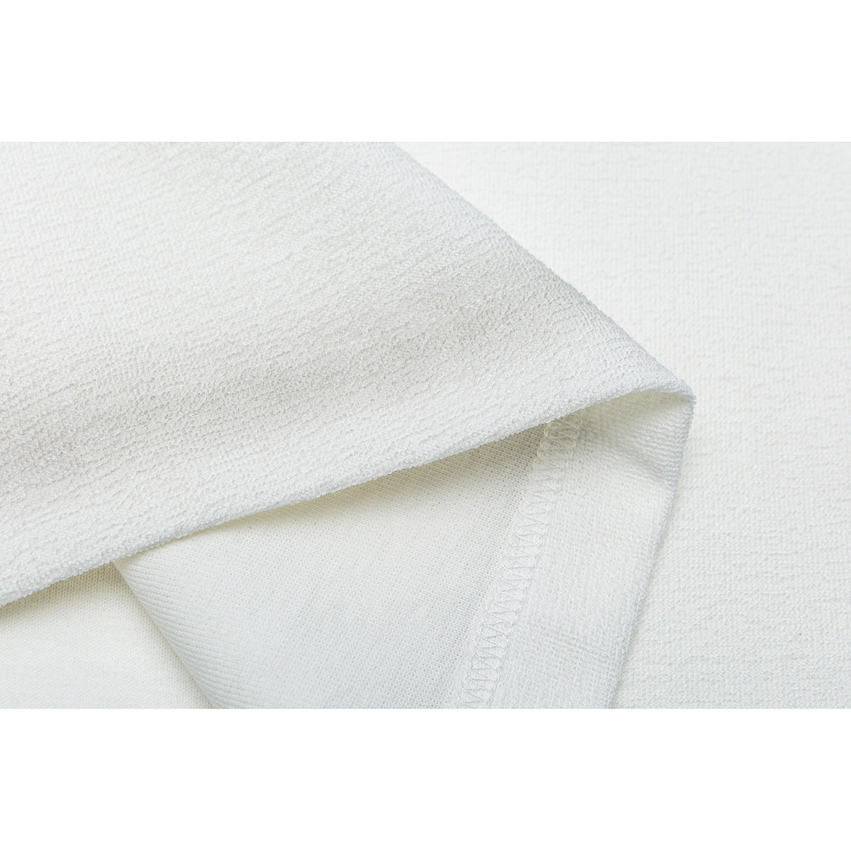 Close-up of white garment fabric folded to show the stitched inside seam and hem.