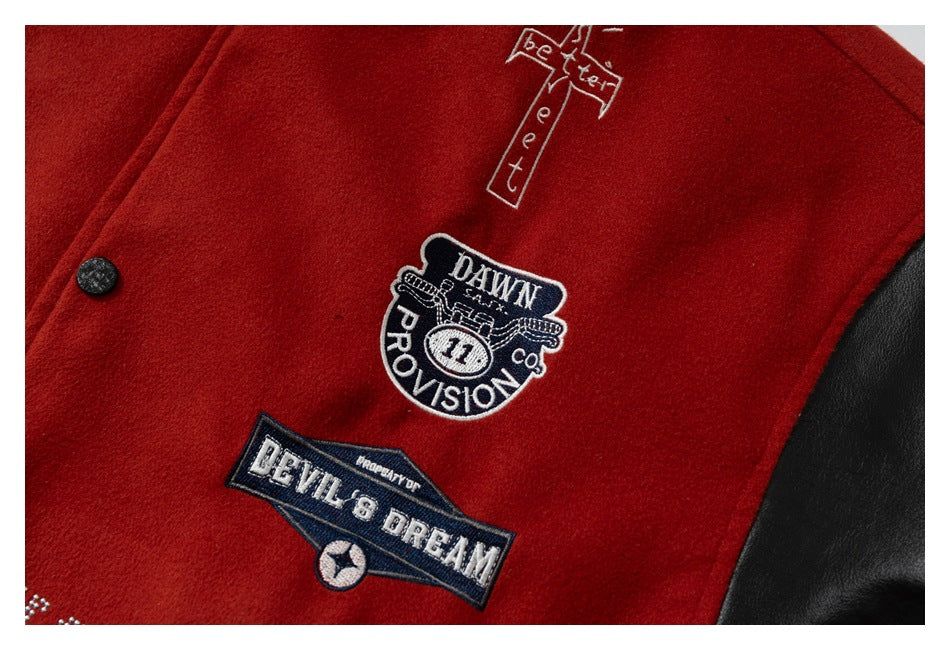 Close-up of embroidered patches and a cross graphic on the red jacket front, with part of a black sleeve visible.