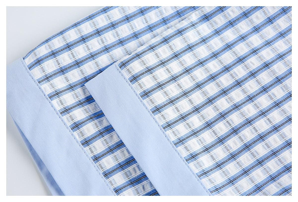 Close-up of blue-and-white striped shirt fabric with a pale blue cuff or trim panel.