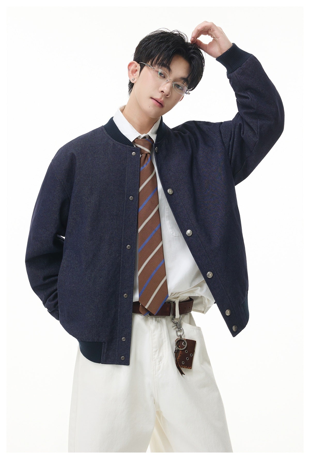 Model wearing an open dark navy bomber jacket over a white shirt and brown striped tie.