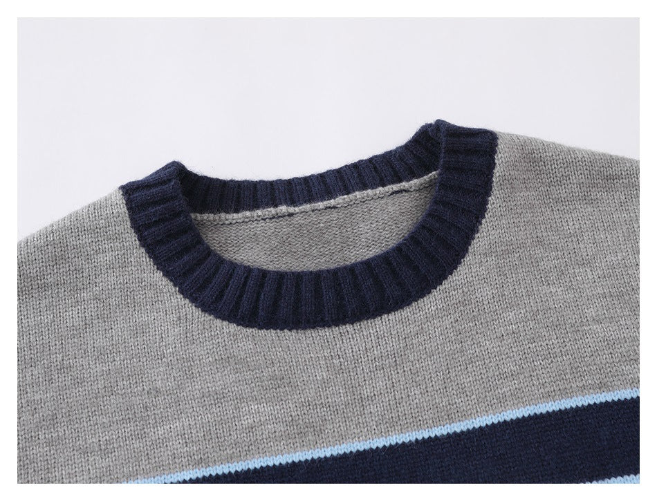 Close-up of a gray sweater's navy ribbed crew neck and upper chest with a light blue and navy stripe.