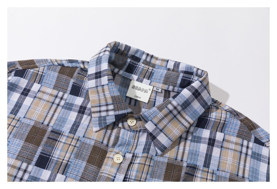 Close-up of a blue, navy, brown, and white plaid shirt collar, placket, buttons, and inner size label.