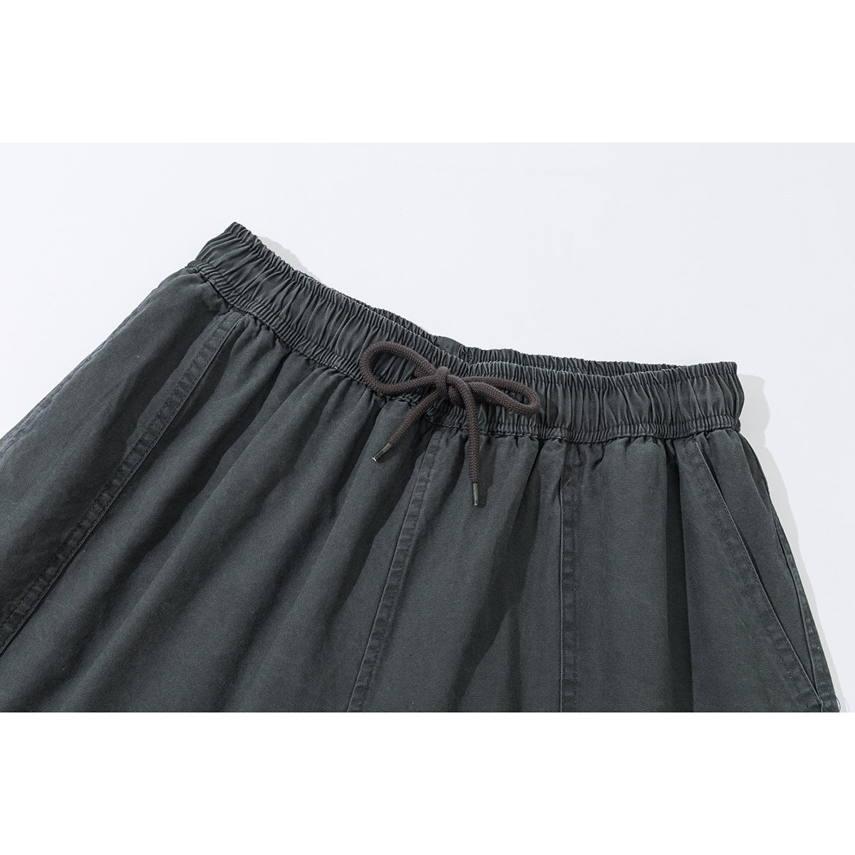 Close-up of charcoal shorts showing an elastic drawstring waistband and angled front pockets.