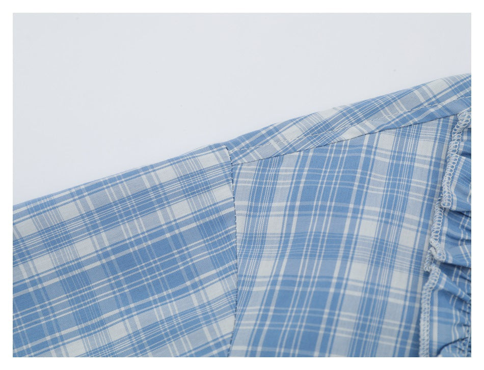 Close-up of a blue-and-white plaid shirt showing the shoulder seam and ruffled edge.