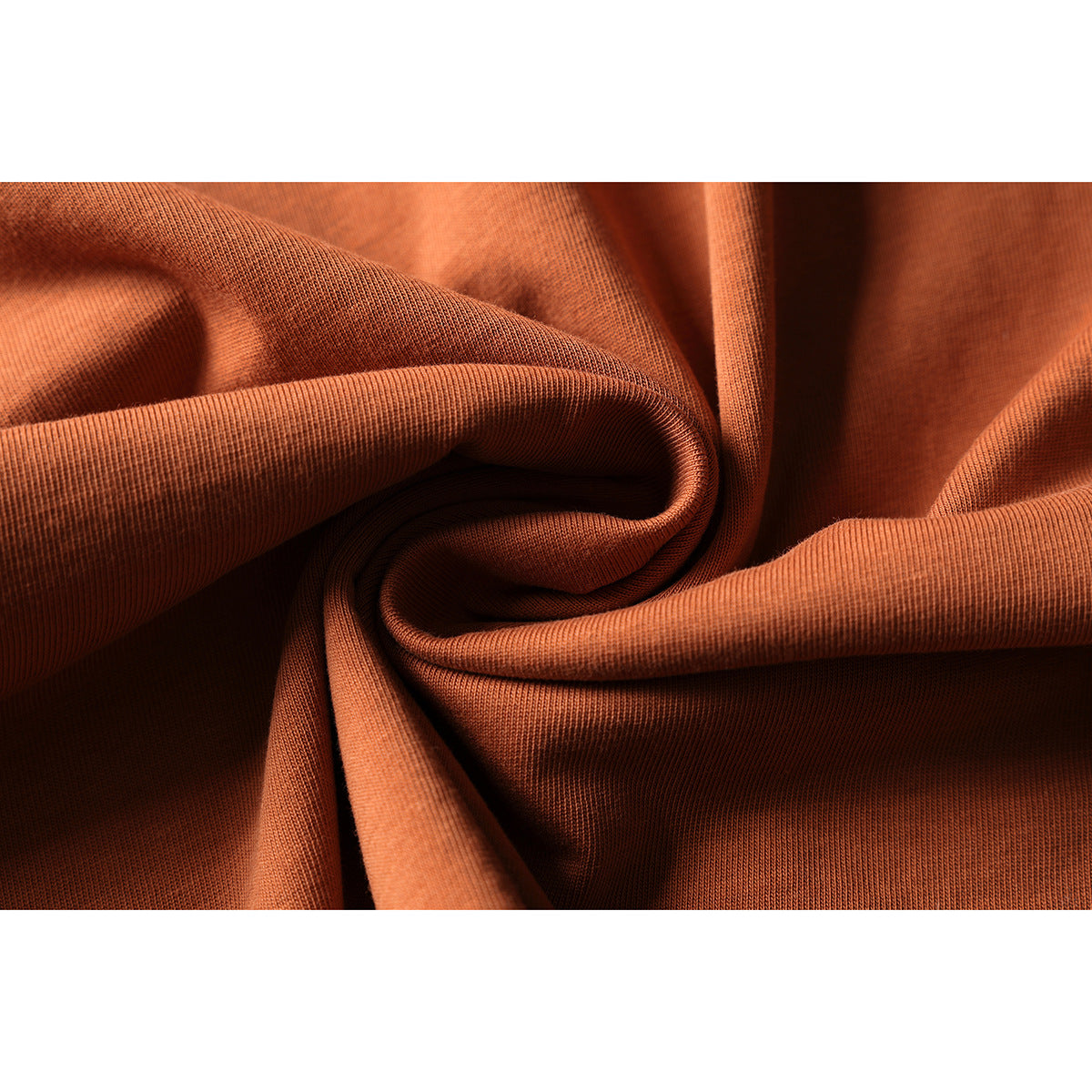 Close-up of rust-orange knit fabric arranged in soft folds, showing its surface texture.