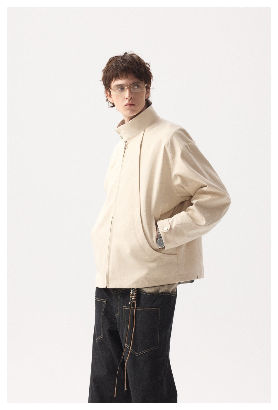 Model wearing a light beige jacket with a high collar and snap-cuff sleeves, shown at a three-quarter angle.
