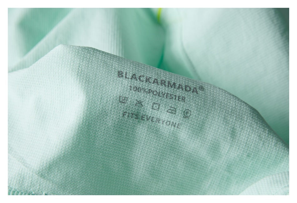 Close-up of a garment's BLACKARMADA label, care symbols, and polyester text on mint fabric.