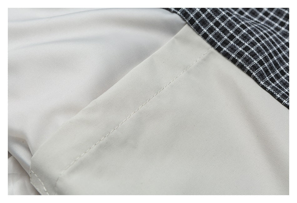 Close-up of an off-white garment seam beside black-and-white checked fabric.