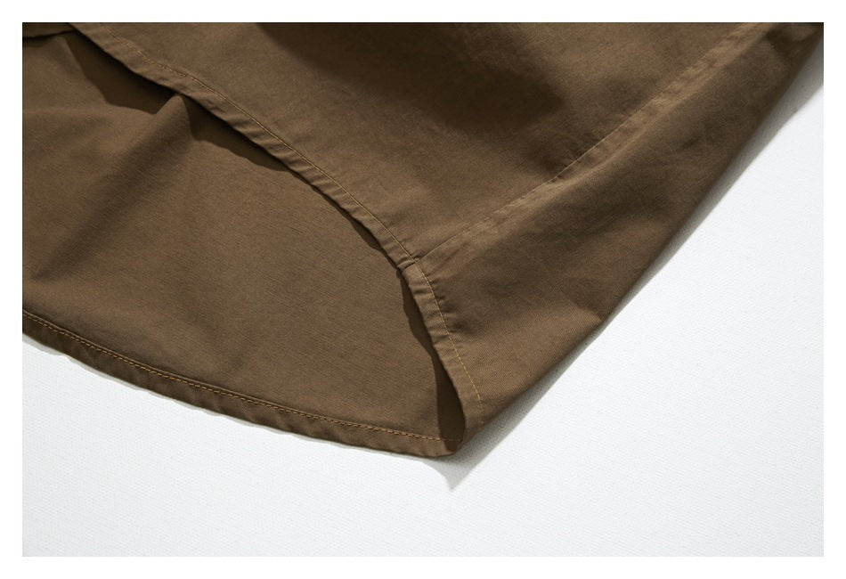 Close-up of the curved stitched hem and overlapping panels of a brown shirt.