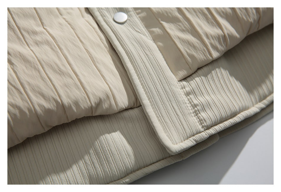 Close-up of the cream jacket’s snap placket, crinkled panels, and ribbed hem.