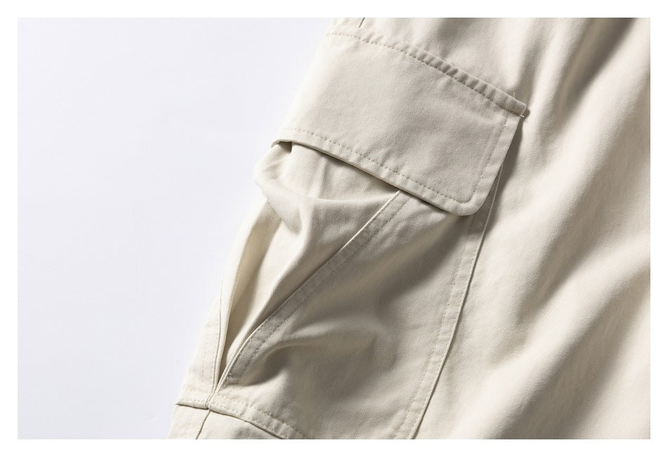Close-up of a light beige cargo pocket flap and stitched pocket on the shorts.