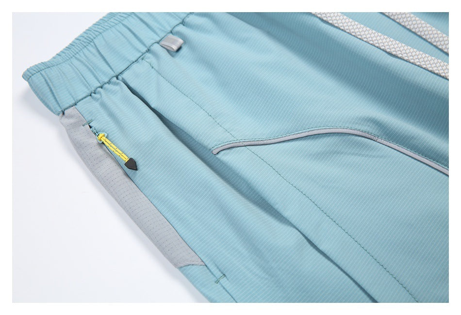 Close-up of light blue shorts showing an elastic waistband, gray side panel, and yellow zipper pull.