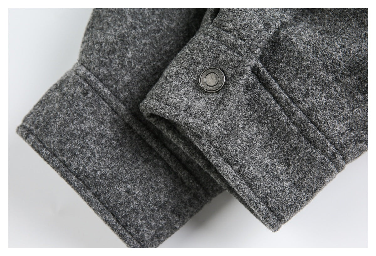 Close-up of a charcoal gray garment cuff with a flap and dark metal snap button.