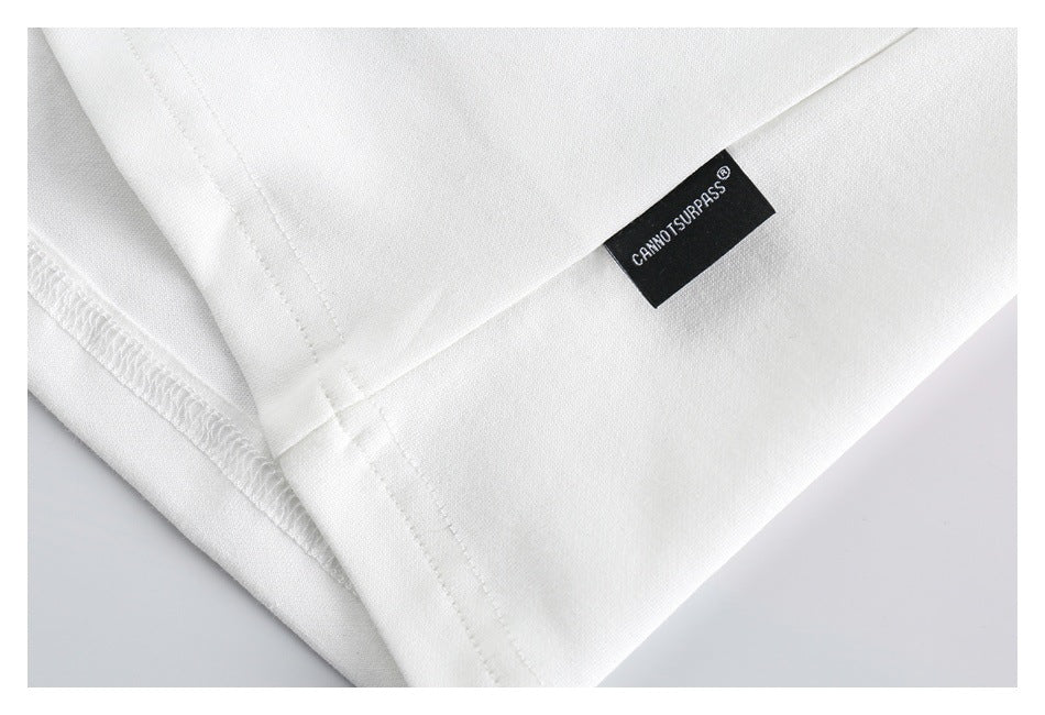 Close-up of a black CANNOT SURPASS label stitched onto white fabric near a seam.