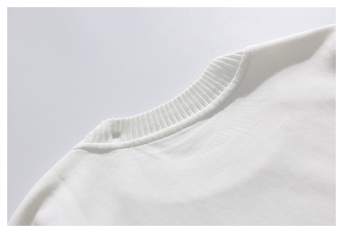 Close-up of a white garment with a ribbed crew neckline and smooth body fabric.