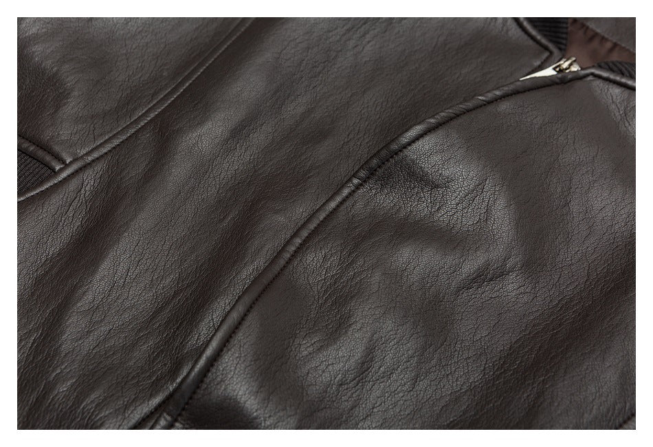 Close-up of dark brown leather-look jacket material with curved piping and a glimpse of a metal zipper.