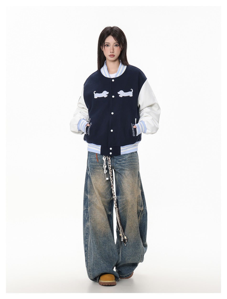 Full-body front view of a model in a navy and white varsity jacket and oversized faded jeans.