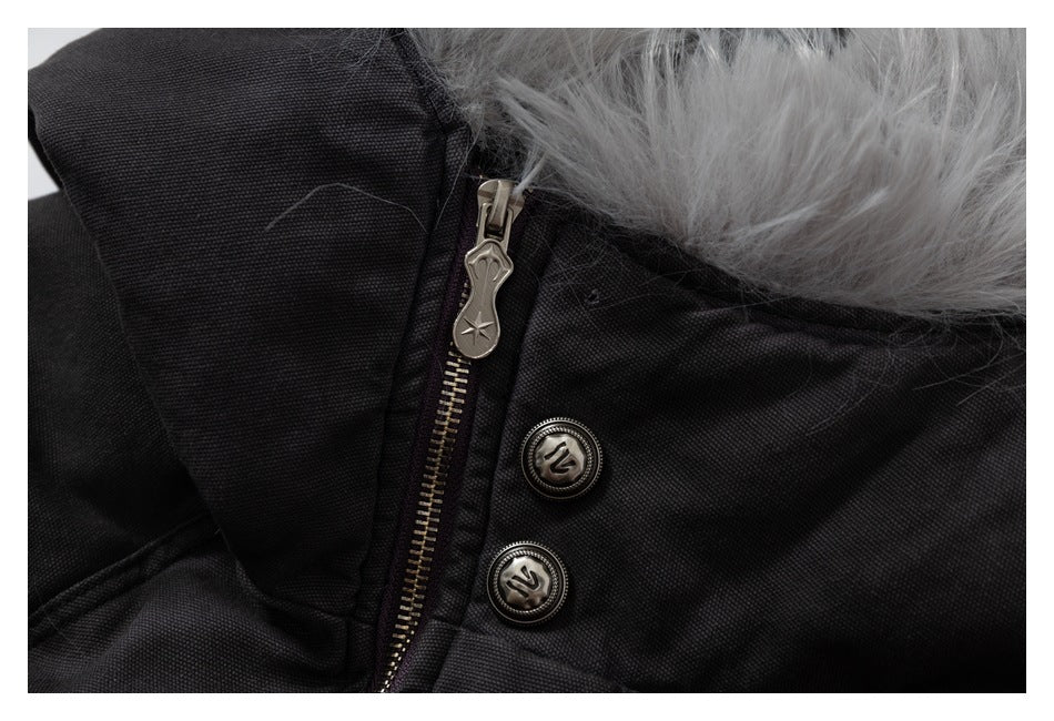 Close-up of a black jacket collar with gray faux-fur trim, a metal zipper, and two emblem buttons.
