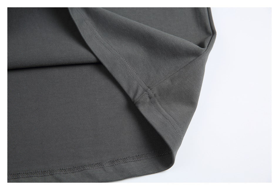 Close-up of a charcoal garment hem with visible stitching and folded fabric.