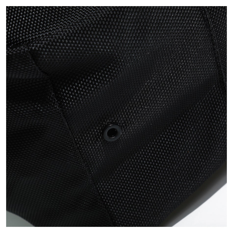 Close-up of a small circular black metal eyelet on textured bag fabric.