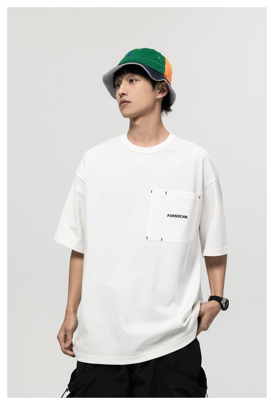 Model wearing a white oversized T-shirt with a stitched chest pocket and black text, shown at a slight angle.