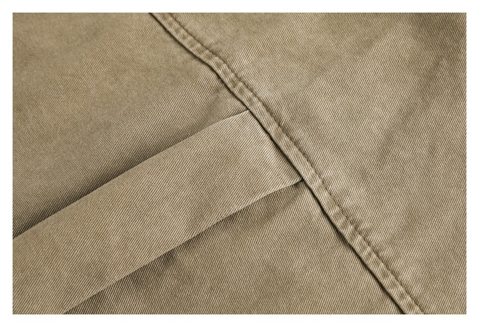 Close-up of tan garment fabric with a stitched seam and a narrow overlapping strip.