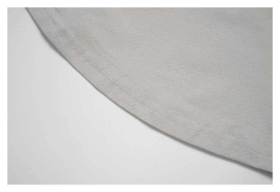 Close-up of the curved double-stitched hem on a light gray top.