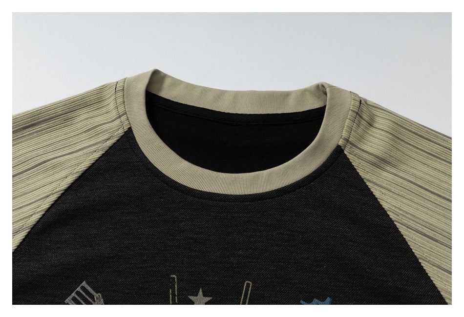 Close-up of the beige crew neck and striped raglan sleeves against the black front of the T-shirt.