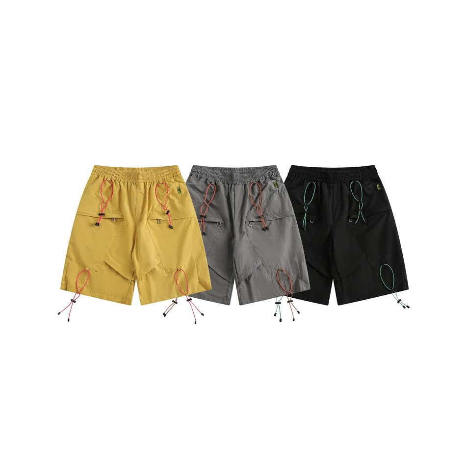 Front views of mustard, gray, and black shorts, each with an elastic waist, pockets, and contrasting cords.