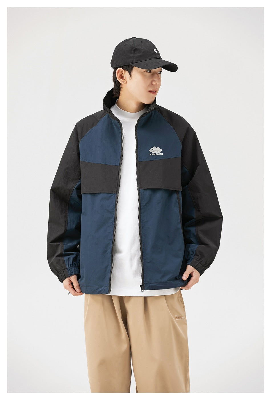 Closer front view of a model wearing a navy and black color-block zip jacket with a high collar.