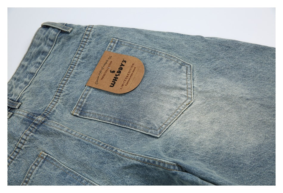 Close-up of the back pocket on light blue washed jeans with an attached tan English-text patch.