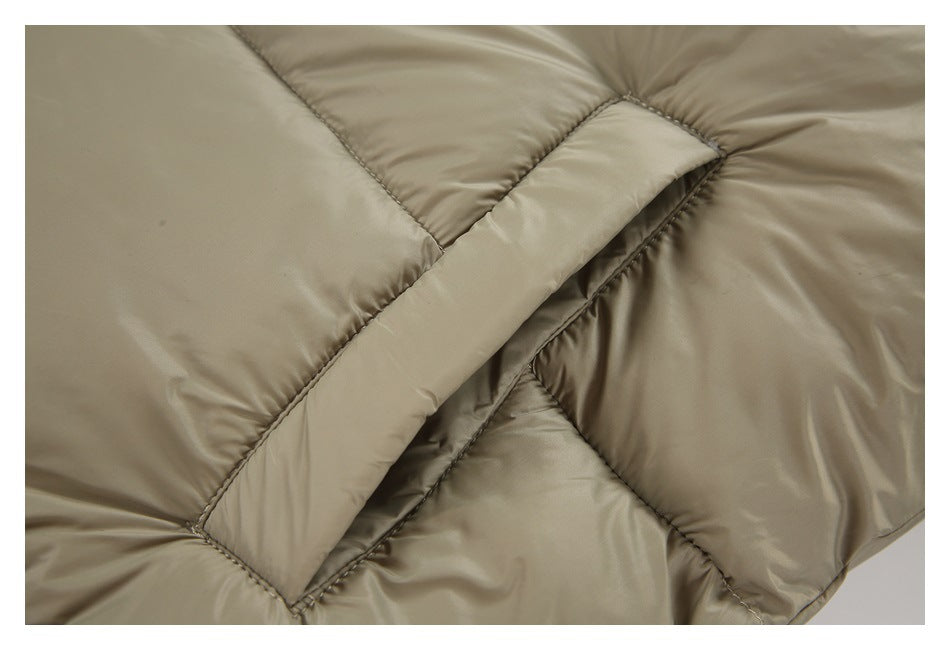 Close-up of a stitched diagonal pocket opening on the light-taupe padded jacket.