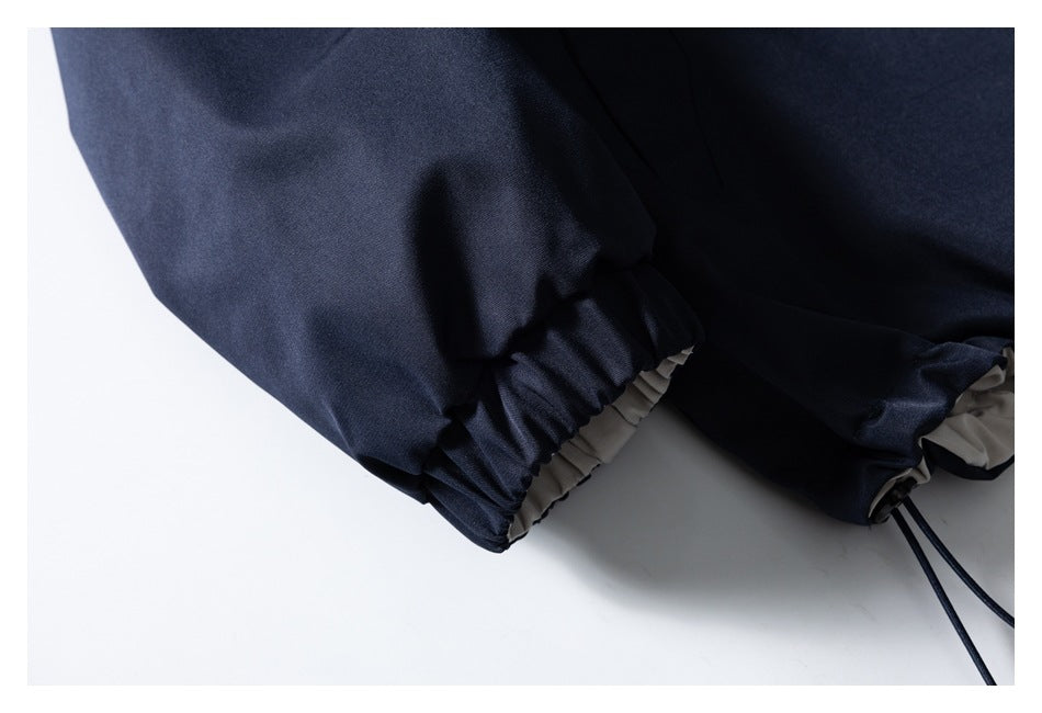 Close-up of a navy jacket's elastic cuff, contrasting light lining, and hem drawcord.