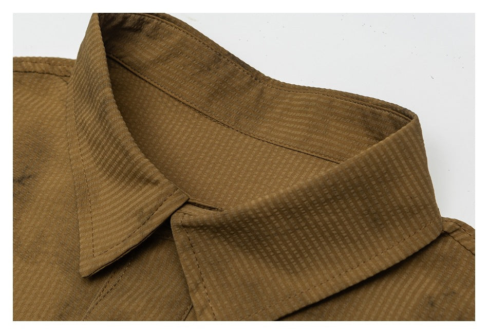 Close-up of a brown shirt's pointed collar, showing a subtle woven check texture and stitching.