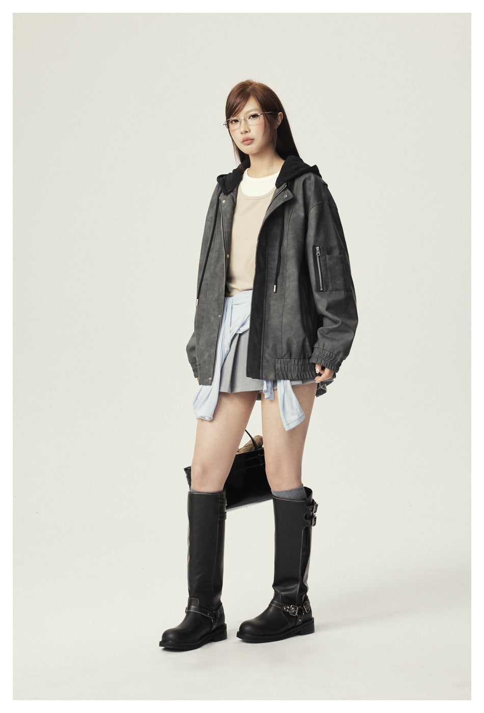 Front view of a model wearing an oversized charcoal hooded jacket with a zip sleeve pocket, elastic cuffs and hem.