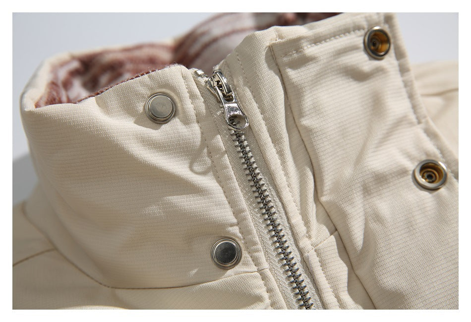 Close-up of a beige jacket's front zipper and metal snap closures.
