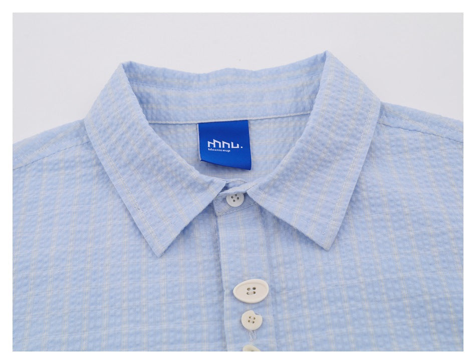 Close-up of the light blue shirt collar, top buttons, and a blue sewn-in neck label.