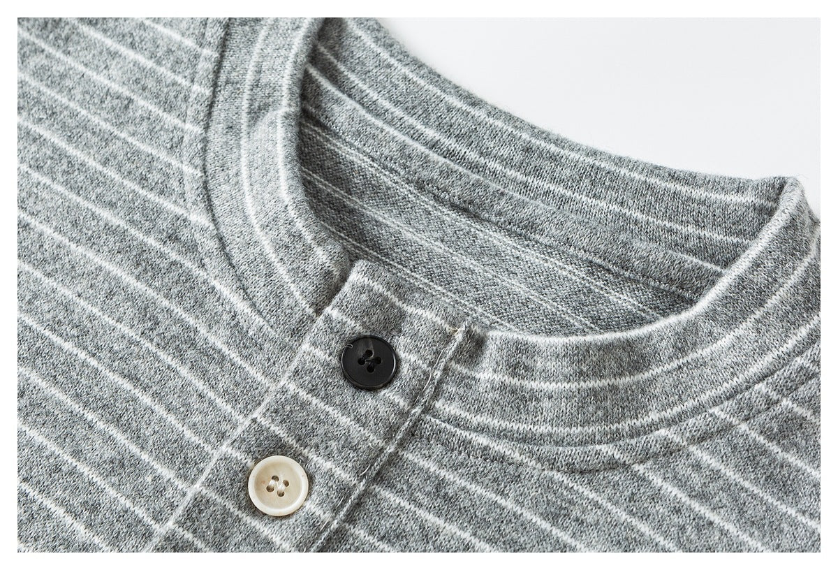 Close-up of the gray-and-white striped shirt's round neckline and placket with dark and cream buttons.
