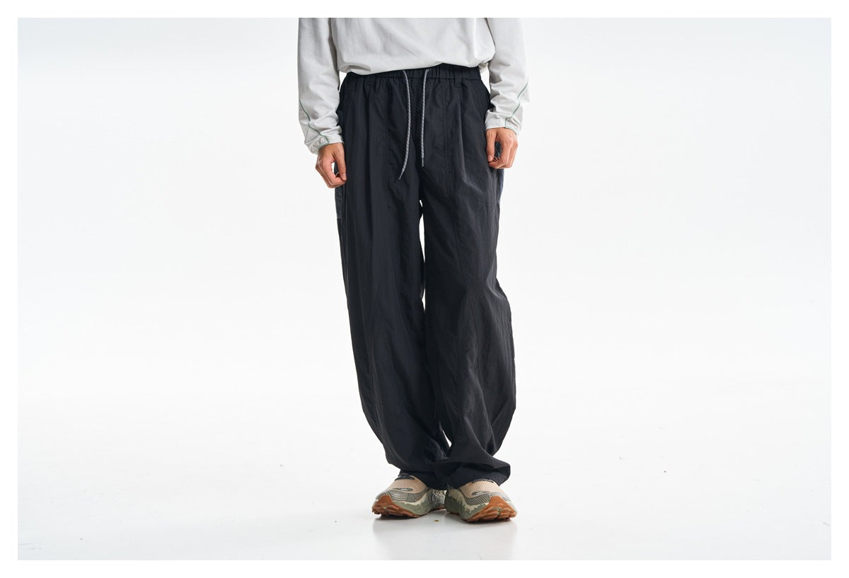 Cropped model wearing loose black drawstring pants with a white top and patterned sneakers, front view.