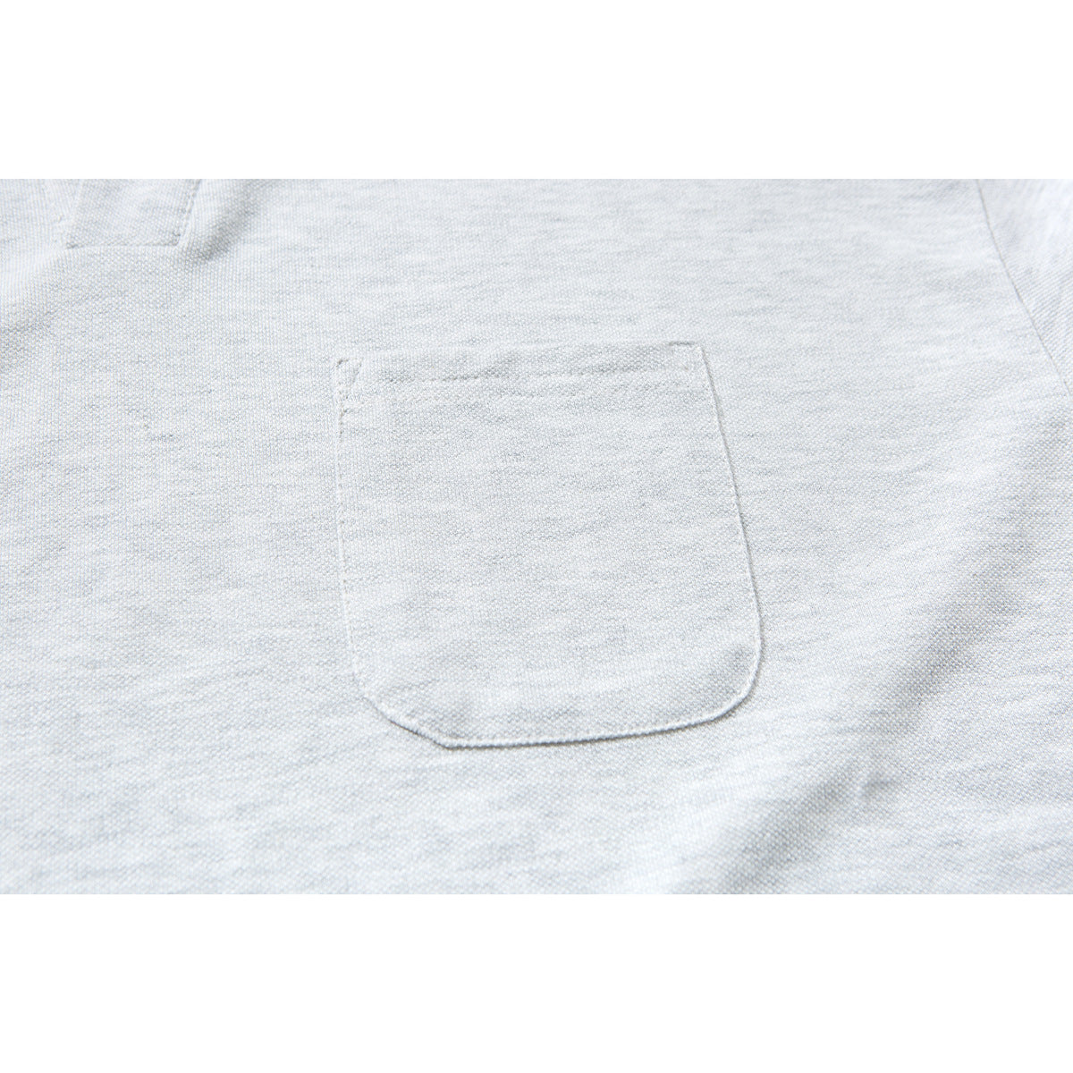 Close-up of the stitched chest pocket on a light gray polo shirt.