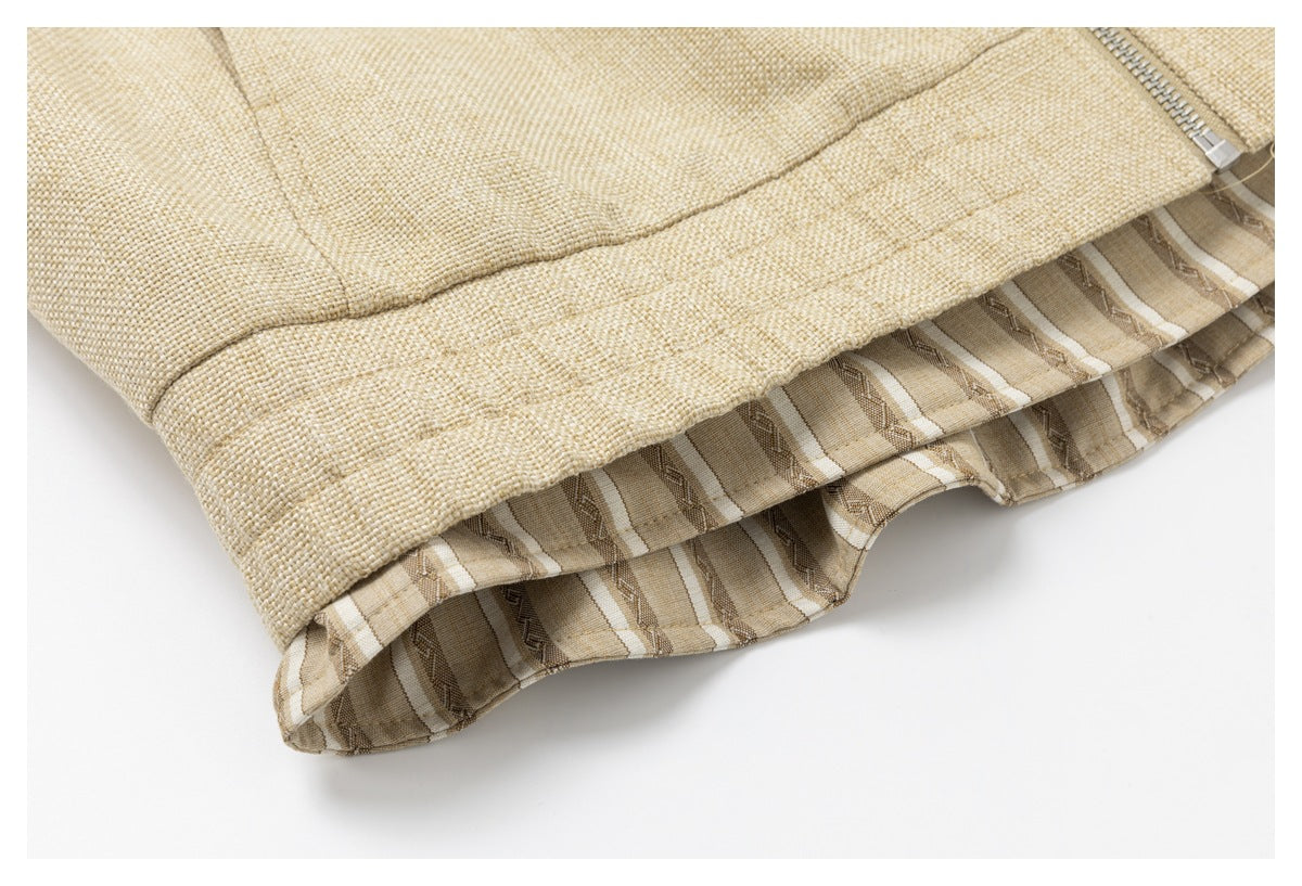 Close-up of the beige jacket hem with striped patterned lining and a metal zipper.