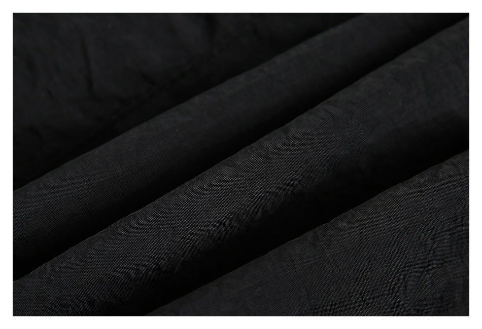 Close-up showing the dark, subtly textured black garment fabric in soft folds.
