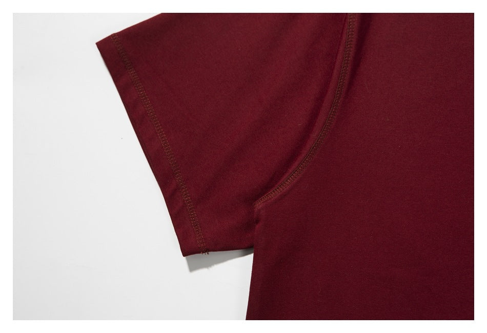Close-up of the burgundy T-shirt's short sleeve and curved underarm seam.
