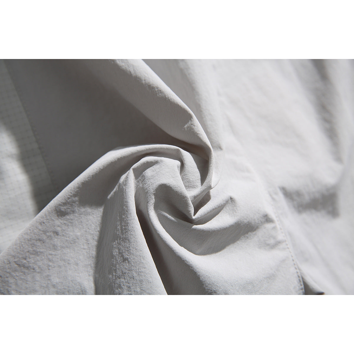 Close-up of white shorts fabric gathered into folds, showing its surface and texture.